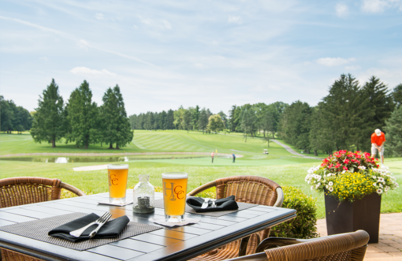 Dining table with Hershey Country Club branded glasses overlooking golf course and golfer.