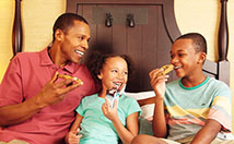Family eating cookies and milk in bed while laughing
