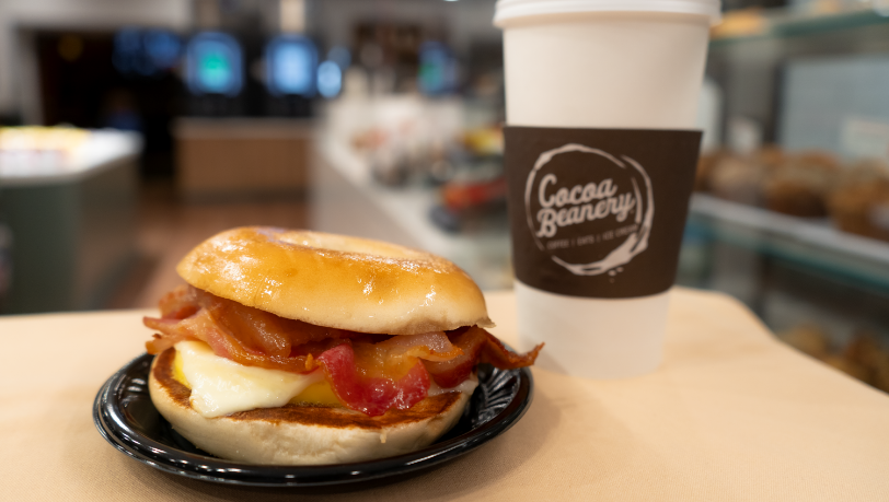 Egg and cheese sandwhich with bacon and a side of coffee.