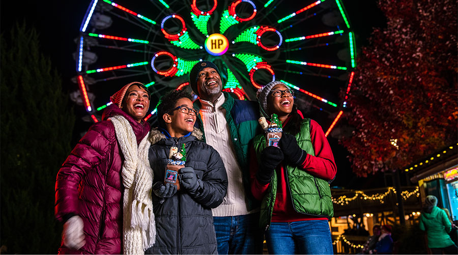 Family at Hersheypark Christmas Candylane with ferris wheel in the background.