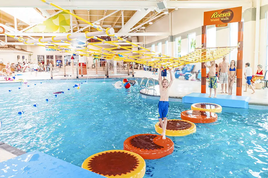 Little boy climbing across the Reese's Water Walk rope course at the indoor water park at the Hershey Lodge.