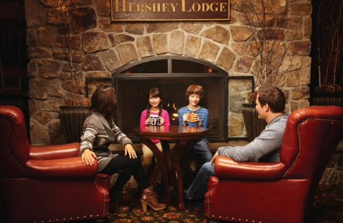 Family drinking hot chocolate by the Hershey Lodge Fireplace