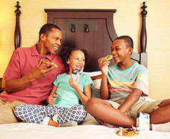 Father with his kids eating cookies on a bed in Hershey Lodge